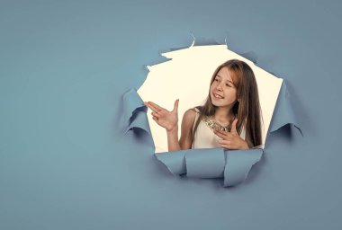 Uzun saçlı neşeli bir çocuk. Çocuk fotokopi alanını işaret ediyor. Çocuk modası ve güzellik.