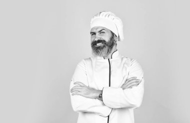 Aşçı üniforması giymiş profesyonel bir aşçı. Hazırlık ve aşçılık konsepti. Mutfak ve mutfak. Sağlıklı yemek pişirme. Sakallı şef üniforması. Sakallı adam mutfakta yemek yapıyor.