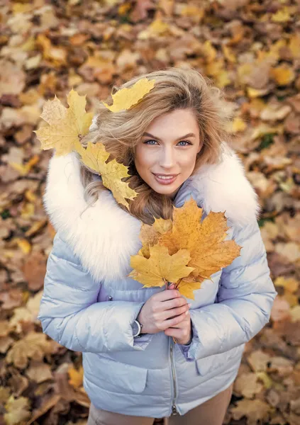 날씨가 좋으면 기분이 좋아. 마른 낙엽을 두르고 있는 소녀. 따뜻 한 옷을 입는다. 편안하고 편안하고. 가을 패션. 아름다움과 스타일. 잎이 달린 긴 털을 가진 여인 — 스톡 사진