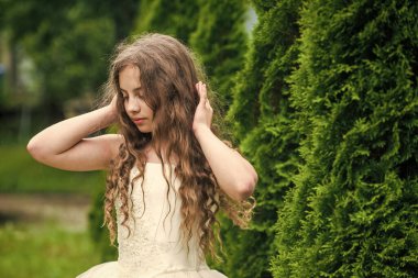 Beyaz elbise giyen uzun kıvırcık saçlı güzel kız, masumiyet ve şefkat kavramı.