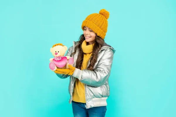 Детство. Девочка-подросток держит игрушечного медведя. ребенок в теплой одежде на синем фоне. — стоковое фото