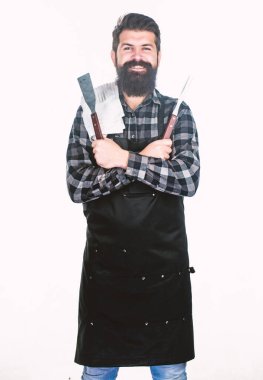 Barbekü seti kullanarak. Kendine güvenen ızgara aşçısı. Izgara tutucu aletleri tutan sakallı adam. Barbekü ızgara için metal mutfak eşyaları ile önlük Hipster. Izgarada yemek hazırlama