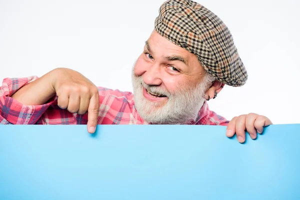 Pubblicità persone anziane. Affascinante pensionato in cappello d'epoca tenere poster informazioni copia spazio. Informazione del pubblico. Concetto di annuncio. Senior barbuto sbirciare fuori banner luogo informazioni — Foto Stock