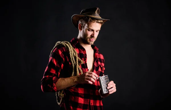 Cowboy beve. Camicia a scacchi da uomo al ranch. Wild West Rodeo. uomo in cappello sfondo nero. cowboy con corda di lazo. Occidentale. Uomo in stile vintage. Un cowboy retrò del Wild West. western cowboy ritratto — Foto Stock