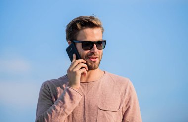 Başvuru ve internet. Hippi güneş gözlüğü takıyor cep telefonuyla gökyüzü arka planı tutuyor. Hippi akıllı telefon görüşmesi. Önemli bir cep telefonu sohbeti. Adam cep telefonu. İrtibatı koparmayalım. Mobil çağrı kavramı
