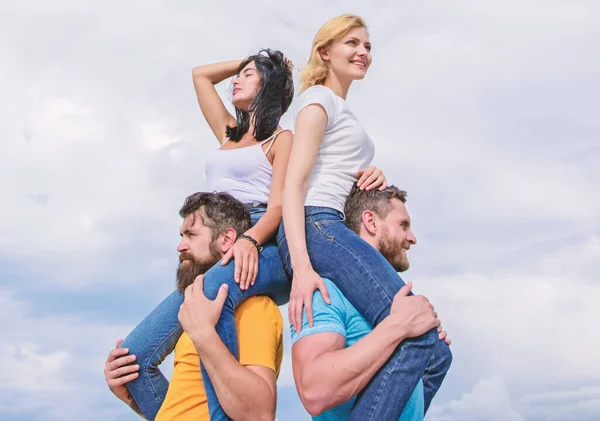 Taking real pleasure. Playful couples in love smiling on cloudy sky. Loving couples having fun activities outdoor. Loving couples enjoy fun together. Happy men piggybacking their girlfriends — Stock Photo, Image