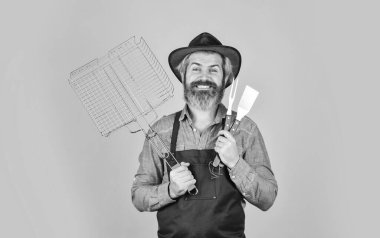 Biftek pişiriyorum. Mutfak aletleri. BBC ekipmanlı bir çiftçi. Yaz pikniği. BBQ Amerikan geleneği. Mutfak konsepti. Bekarlığa veda günü. Orta pişmiş. Et kızartan aletler. Önlüklü adam barbekü ızgarası yapıyor.