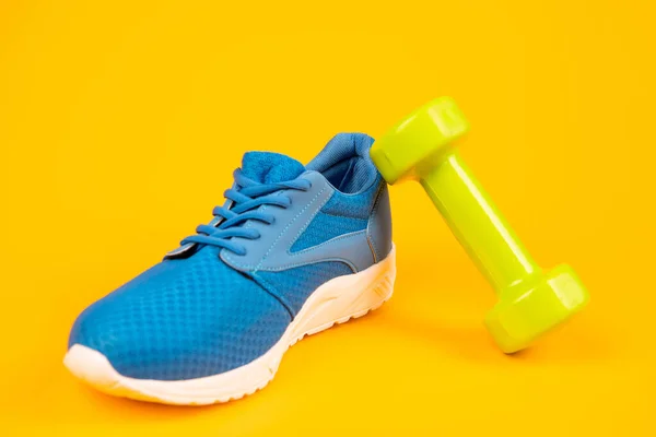 Bequemer Schuh mit Langhantel. sportliche blaue Turnschuhe. Schuhe auf gelbem Hintergrund. — Stockfoto