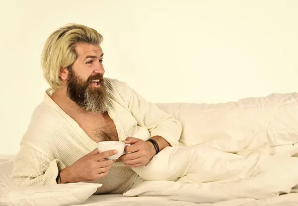 Spending great time at home. Guy in bath clothes hold coffee. Morning rituals. Tired man drinking coffee. Every morning begins with coffee. Bachelor in bathrobe. Man with beard in dressing gown