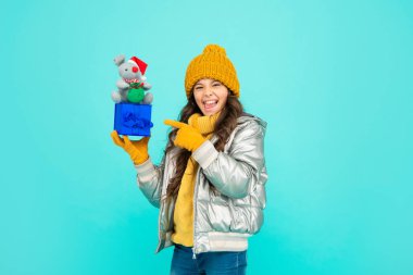 Mavi arka planda sıcak kıyafetler giyen mutlu çocuk. pozitif duygularını ifade et.