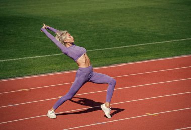 Enerji dolu. Atletik bayan stadyumda ısınıyor. Kadın sporcu spor yapıyor.