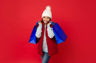 Kırmızı arka planda örgü şapkalı genç kız alışveriş çantası, indirim.