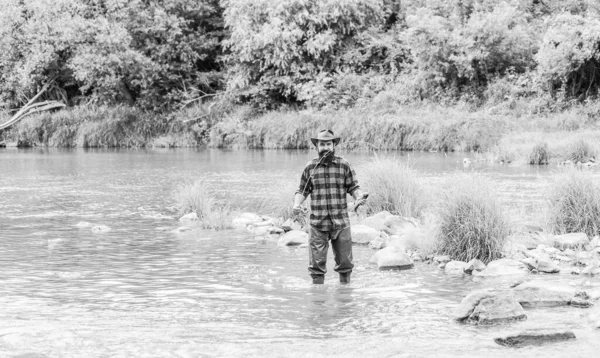 Фішер чоловіче хобі. Риба на гачку. Брутальний чоловік у гумових чоботах стоїть у воді річки. Задоволений рибалка. Рибальство вимагає, щоб ви були уважні й цілком присутні в даний момент. Риболовецька техніка — стокове фото