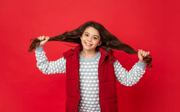 Χαρούμενο παιδί με σγουρά μαλλιά το χειμώνα κάτω γιλέκο σε κόκκινο φόντο, χειμώνα — Φωτογραφία Αρχείου