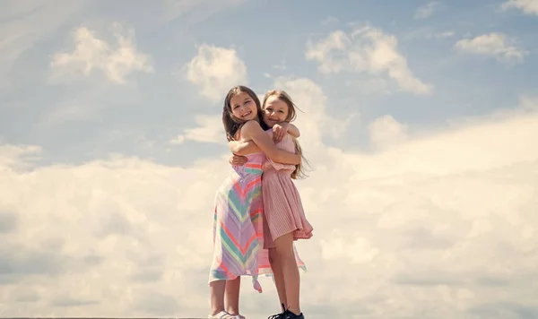 Stile moda bambino. amicizia femminile o sorellanza. infanzia felice. bambini carini su sfondo cielo. stagione primaverile tempo. estate look alla moda. amore di famiglia. belle ragazze adolescenti sorelle abbracciano — Foto Stock