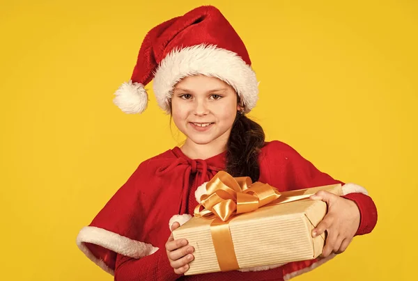 Paquete regalo. Feliz Navidad y felices fiestas. Vacaciones de invierno. Concepto de lista de deseos. Mi feliz día. Compras de regalos de Navidad. Pequeña niña Santa sombrero celebrar caja de regalo. Kid hold caja actual fondo amarillo —  Fotos de Stock