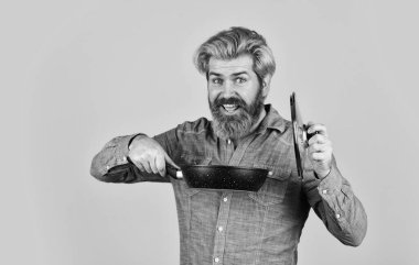 Sağlıklı yemek pişirmek. İsimsiz dökme demir pişirme kabı. Tencerenin cam kapağı. Yapışkan olmayan kaplamalı politetrafluoretilen teflon. Adam yeni marka tavayı tutuyor. Mutfak gereçleri. Mutfak aletleri