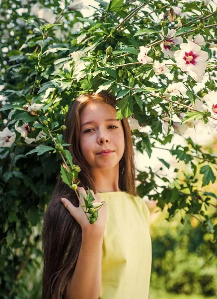 Dospívající dívka blízko rozkvetlého ibišku. dítě na kvetoucím stromě. dítě vychutnat keř květiny. — Stock fotografie