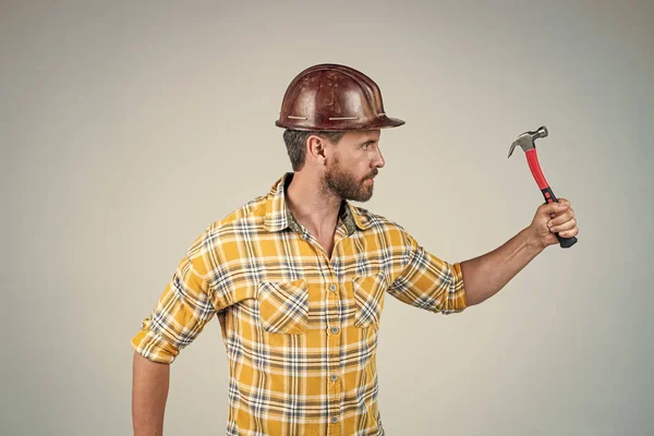 Reparaturen durchführen. Mann Architekt mit Hammer. Typen tragen Arbeiteruniform. schöner Bauarbeiter mit Helm. Älterer Mann trägt kariertes Hemd. professioneller Konstrukteur oder Mechaniker. Bauingenieur — Stockfoto