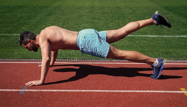 Mann macht Liegestützübung im Stadion. Fitnessstudio im Freien. muskulöser athletischer Typ beim Training. Sport. männliche Stärke und Macht. Sportler in Planke. Sportler machen Liegestütze. trainiert seine Kernmuskulatur — Stockfoto