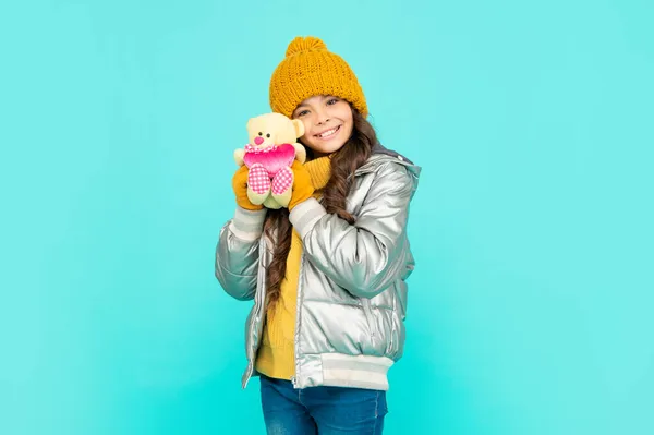 Menina adolescente feliz em roupas de inverno segurar brinquedo no fundo azul, infância — Fotografia de Stock