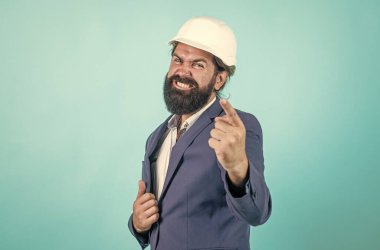 Sakallı işçi. Sırada sen varsın. Mutlu ya da agresif kasklı olgun bir mimar. Vahşi sakallı adam şantiyede çalışıyor. Proje üzerinde çalışıyorum. bina konsepti. İnşaatçı ya da mühendis.