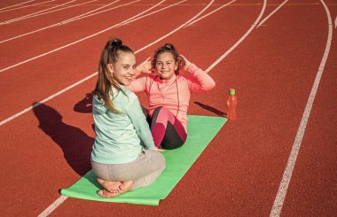 Zihin ve beden uyum içinde. pilates. Çocuklar beden eğitimi dersinde eğitim görüyorlar. Matta üzerinde yoga yapan genç kızlar. Meditasyon. Bedenle uyum içinde ol. Stadyumda ortam ısınıyor.
