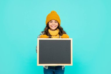 Kış alışverişi. Okula dönüyorum. Şapkalı mutlu çocuk tahtayı tutuyor. çocukluk.