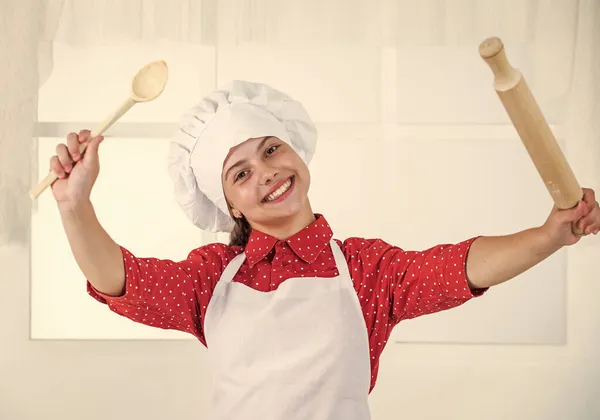 Criança segure colher de madeira e rolo de pino, cozinhar — Fotografia de Stock