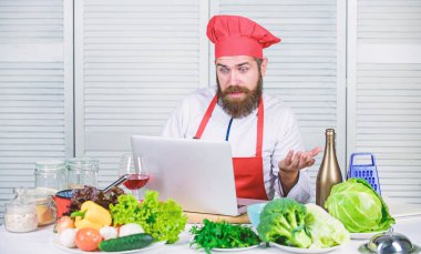 Mutfak Okulu. Şapka ve apron online yemek nasıl öğrenme hipster. Mutfak eğitimi online. ELearning konsepti. Adam şef internet tarifi yemek yemek arıyor. Chef laptop yemek tarifleri okumak
