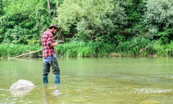 Lagunenteich am Fluss. Forellenzucht. In der Fischzucht werden Fische kommerziell gezüchtet. Allein die Fischer stehen im Flusswasser. Mann bärtiger Fischer. Fischerausrüstung. Hobby-Sport — Stockfoto