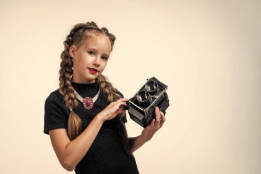 Genç kız fotoğraf çekiyor. Retro kamera. Mutlu çocukluk. Çocuğun şık bir görünüşü var. Modern hayatta fotoğrafçılık. Eski moda fotoğraf makinesi olan çocuk beyaza izole edilmiş. Eski teknoloji. Boşluğu kopyala