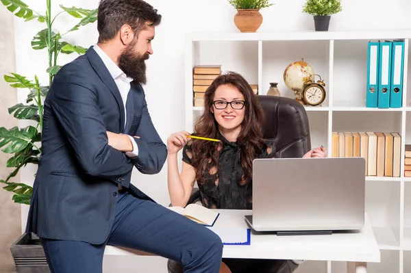 工作时快乐的职业女性，而穿着西装的男性则坐在办公桌前工作 — 图库照片