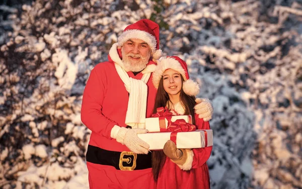 すごい驚きですね。小さい女の子とサンタの衣装のおじいちゃん。サンタは屋外を提示するヘルパー。美しい雪の冬。子供と先輩お祝いの準備ができています。冬休み — ストック写真