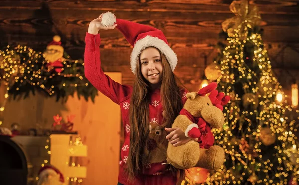 Kış tatili Noel Baba kostümü giymiş neşeli bir çocuk. Çocuklar Xmas 'ı sever. Küçük mutlu kız ren geyiği oyuncağı hediye ediyor. Yeni yıl partisi kutlaması. Noel zamanı geldi. Gelmiş geçmiş en iyi hediye. çocukluk mutluluğu — Stok fotoğraf