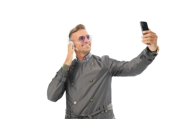 Homem bonito feliz usar smartphone ouvindo música em fones de ouvido isolados em branco, chamada de vodeo — Fotografia de Stock