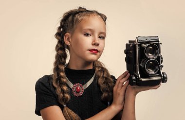 Fotoğraf stüdyosu. Geçmişi olan neşeli kız beyazda izole edilmiş görünüyor. Çocuk modası. Çocuk retro kamerayla fotoğraf çekiyor. Güzellik ve moda. Gazeteci ya da muhabir fotoğrafları. çocukluk mutluluğu