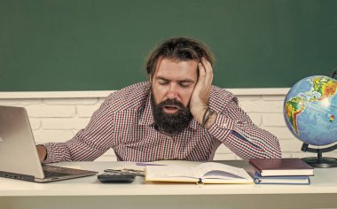 resmi eğitim. Erkek öğrenci zor bir ders sırasında sınıfta oturur. Sınavı geç. Öğrenmek zordur. Stresli hippi öğretmen. Aşırı çalışan, sakallı, stresli bir adam. çalışmada sorunlar