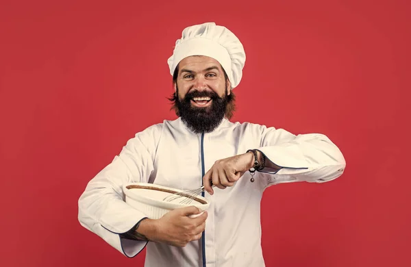 Весело провести час. чоловічий шеф-кухар у капелюсі готує здорову їжу. красивий чоловік з бородою і вусами готує. професійний ресторан готує випічку. кваліфікований пекар використовує кухонне начиння для приготування їжі. відчуває голод — стокове фото