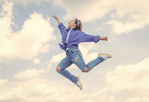 Девушка-подросток в повседневной модной одежде прыгает высоко на фоне неба, энергия — стоковое фото