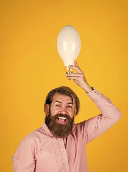 Agy ötlet. Spórolj az energiával. innováció. boldog szakállas férfi kezében villanykörte. kreatív ötlet. inspirált az új ötlet. érett brutális hipszter ötletelés. energiatakarékos lámpa. villamos energia és világítás — Stock Fotó