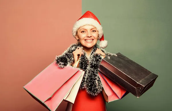 Doe mee. Maak vooraf cadeautjes klaar. Meisjes winkelen. Kerstinkopen. Vrolijk kerstfeest. Vrouwelijke Kerstman hoed houdt papieren tassen vast. Cadeaus kopen. Seizoensgebonden mode. Gelukkig nieuwjaar. Winstgevend winkelen — Stockfoto