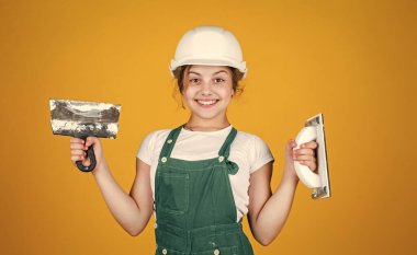 Dünyama hoş geldin. Gelecekteki mühendis. Mutlu çocuk spatula tamir aleti kullanıyor. İnşaat alanı. Çocuk mimar. İşçi Bayramı konsepti. Çocukluk gelişimi. Genç kız asistanı