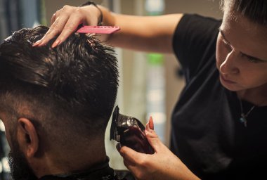 Berber dükkanında yakışıklı hippinin saçını kesen çekici berber, kuaför aletleri.