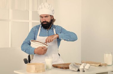 İyi yemek zamanı. Erkek aşçı ev mutfağında yemek hazırlıyor. Önlüklü vahşi hippi yemek pişiriyor. Yemek zamanı. Ciddi pişirme. Oda servisi konsepti. Olgun sakallı adam şef şapkası takıyor.