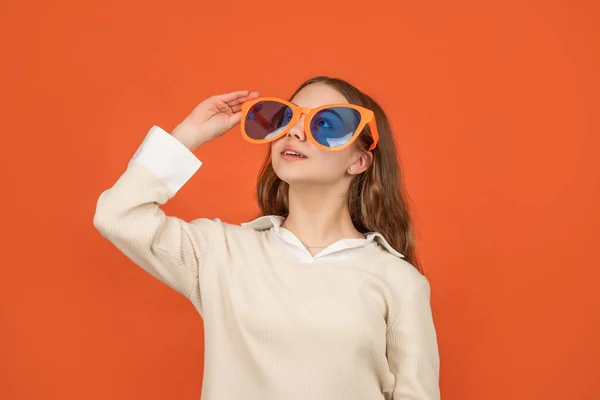 Усміхнена дівчина-підліток в окулярах на помаранчевому фоні, окуляри — стокове фото