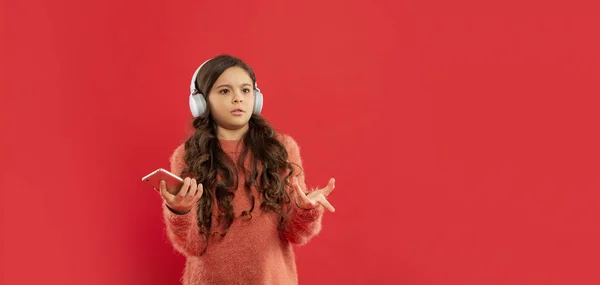 Niño insatisfecho en suéter escuchar música en los auriculares mantener el teléfono, espacio de copia, tecnología — Foto de Stock