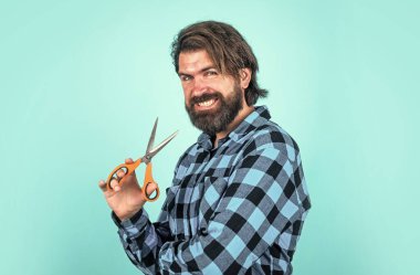 Berber dükkanı. Gülümseyen berber, makas kullan. Saç kesmek için makas kullanan moda bir adam. Kuaför salonundaki kendine güvenen adam. Erkeklik ve karizma. Sakallı hippi sakalını ve bıyığını kesti.