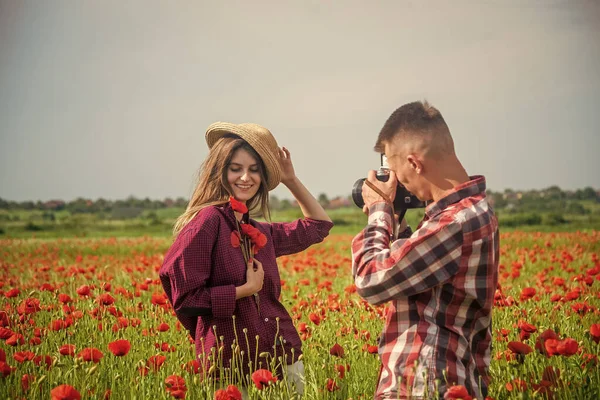 Smekmånadsresa. Lyckliga relationer. flicka och kille i fält med kamera. romantiska par fotografering i röda vallmo blommor. Familjesemester. lycklig man och kvinna kär njuta våren vädret — Stockfoto