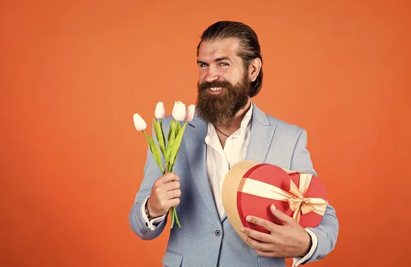 C'est parfait. cadeau pour la journée des mères ou des femmes. homme heureux avec des fleurs de tulipes. gentleman tenir bouquet et boîte de coeur. concept de Saint Valentin. homme avec barbe et cheveux élégants. vacances et célébration — Photo